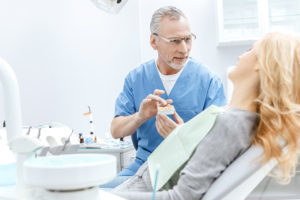 dentist showing jaws model to patient in dental cl LWMSGDQ