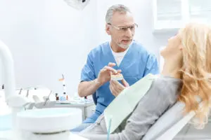 dentist showing jaws model to patient in dental cl LWMSGDQ