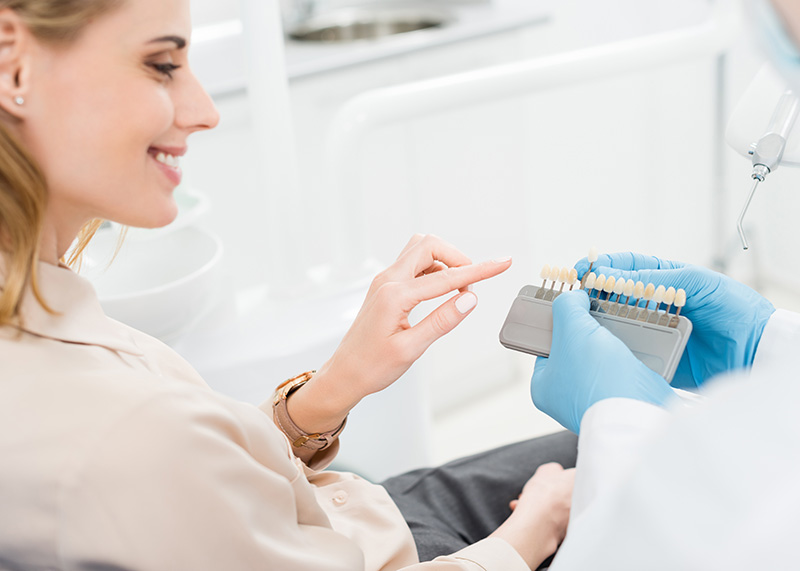 doctor-showing-tooth-implants-to-female-patient-in-9AG2FLZ