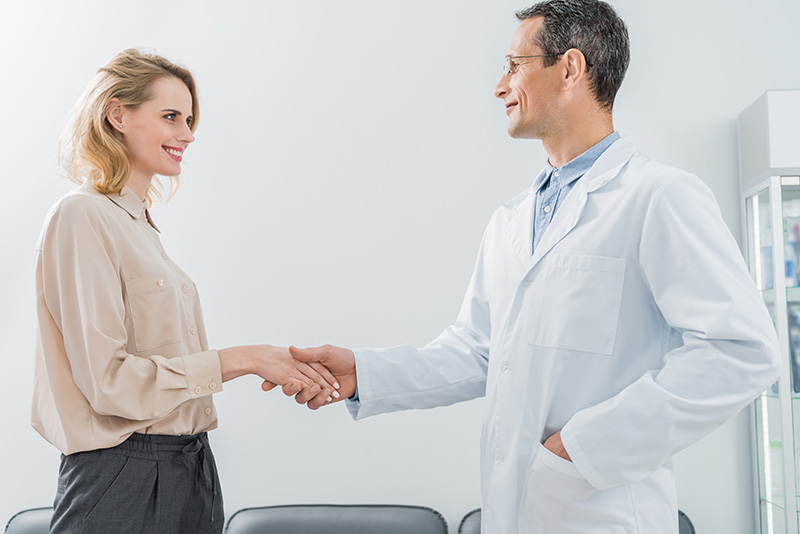 male-doctor-and-female-patient-shaking-hands-in-mo-YRGZXVP